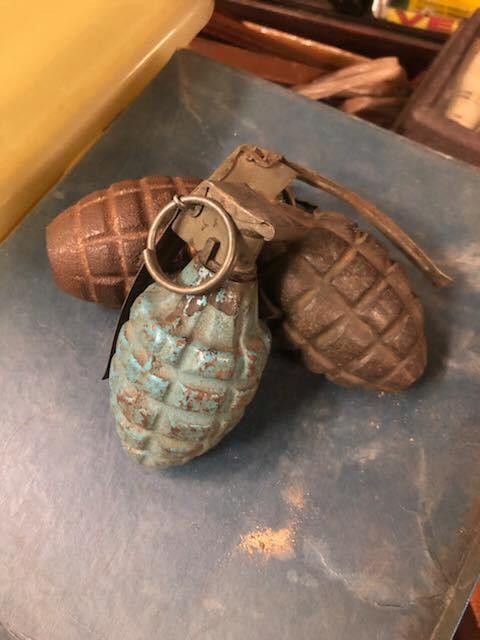 Three vintage hand grenades in various colors resting on a blue surface.