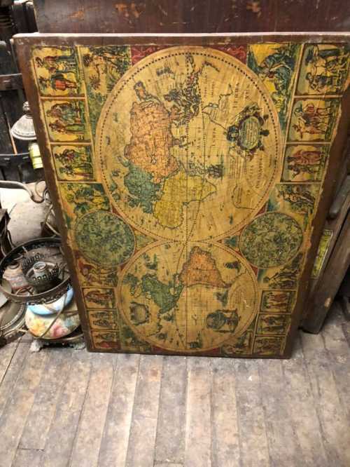 Vintage world map illustration on a wooden board, featuring colorful continents and decorative borders.