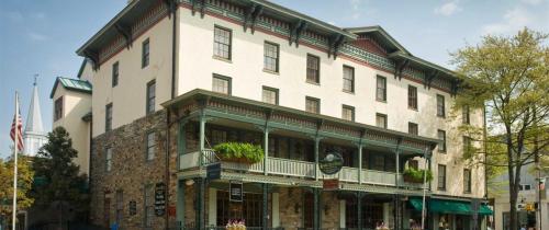 Historic building with a stone facade, green balconies, and large windows, surrounded by trees and flags.
