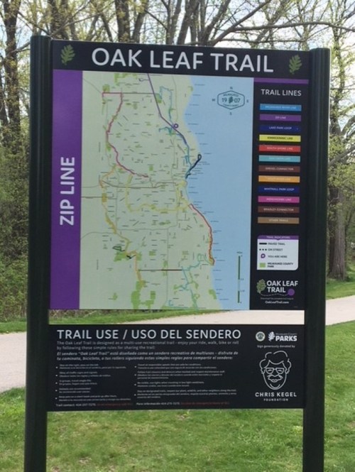 Sign displaying the Oak Leaf Trail map, including trail lines and usage information in English and Spanish.