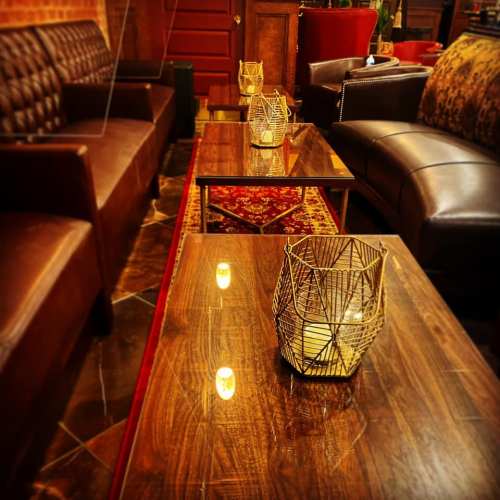 Cozy lounge area with leather sofas, wooden tables, and decorative candle holders, creating a warm ambiance.