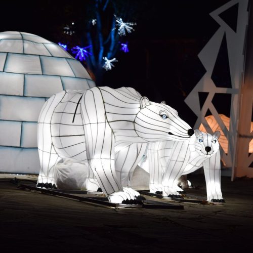 Illuminated polar bear and cub sculptures beside a glowing igloo, set against a dark background.