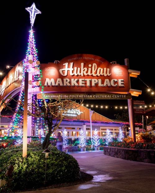 Brightly lit sign for Hukilau Marketplace at night, adorned with festive decorations and a star on top.