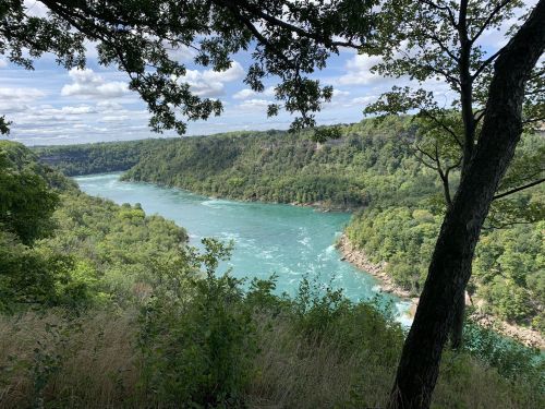 A scenic view of a river winding through lush green hills under a partly cloudy sky.