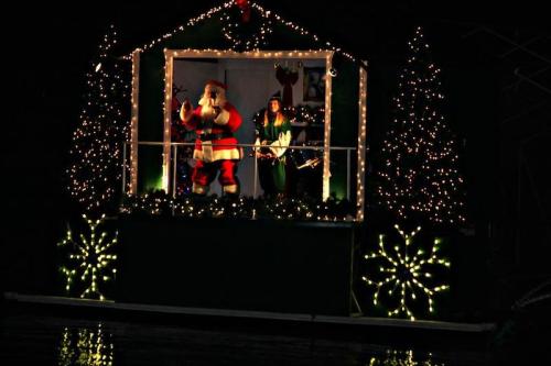 A festive display featuring Santa and an elf, surrounded by twinkling lights and holiday decorations.