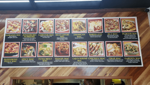 Menu board featuring various macaroni dishes, including Hawaiian, Lobster, Meat Lovers, and more, with vibrant images.