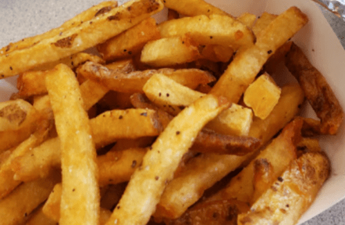 A close-up of golden-brown French fries, some crispy and others slightly darker, served in a white container.
