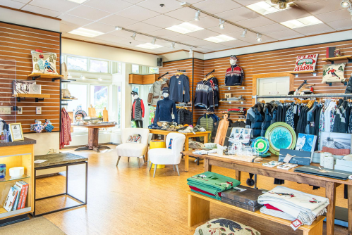 A cozy retail store interior showcasing clothing and accessories on display racks and tables.