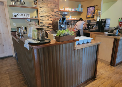 A cozy coffee shop interior with a wooden counter, coffee equipment, and a barista preparing drinks.