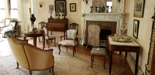 A vintage living room with elegant furniture, a fireplace, and decorative items, creating a cozy atmosphere.