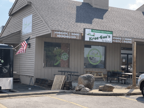 Exterior of Kroeg-Coo's restaurant featuring a sign for Cajun cuisine and an American flag outside.