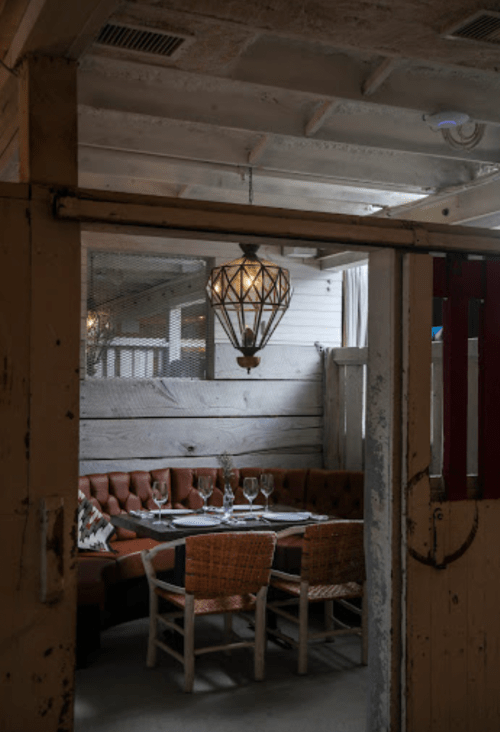Cozy dining area with a wooden table, upholstered seating, and a decorative pendant light. Rustic decor and warm ambiance.