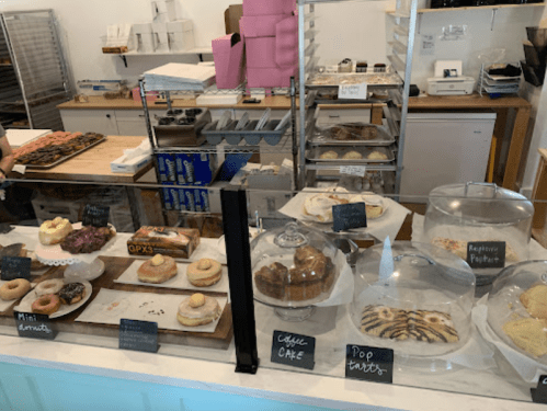 A bakery display featuring various pastries, including donuts, cakes, and pop tarts, under glass domes.