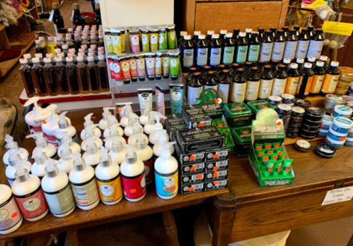A display of various bottles and jars of lotions, oils, and other products on a wooden table in a store.