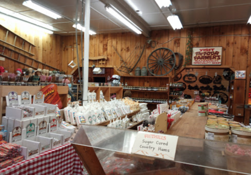 A rustic store interior filled with various packaged goods, jars, and a sign for a farmer's market.