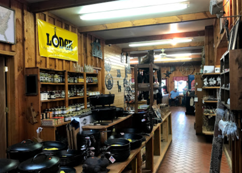 Interior of a rustic store featuring shelves of spices, cookware, and wooden decor, with customers in the background.
