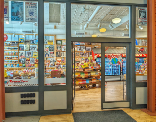 A colorful store entrance filled with various snacks, drinks, and vintage signs, inviting customers inside.