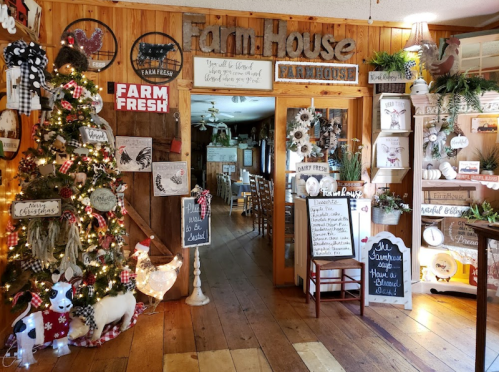 Cozy farmhouse interior decorated for Christmas, featuring a tree, rustic signs, and festive decor.