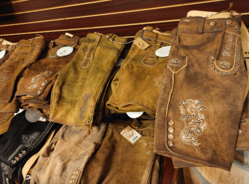 A display of various styles of embroidered leather pants in earthy tones, arranged neatly on a table.