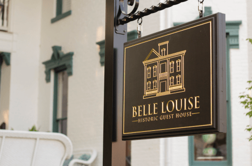 Sign for Belle Louise Historic Guest House featuring a house illustration and elegant lettering.