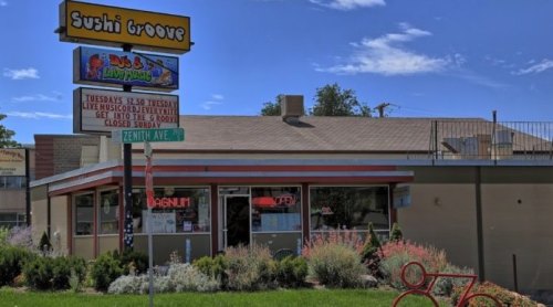 Exterior of Sushi Groove restaurant with colorful signage and a bicycle in front, surrounded by greenery.