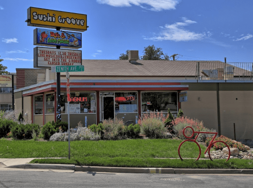 Exterior of Sushi Groove restaurant with a colorful sign, open for business, and a decorative red number "876" in front.