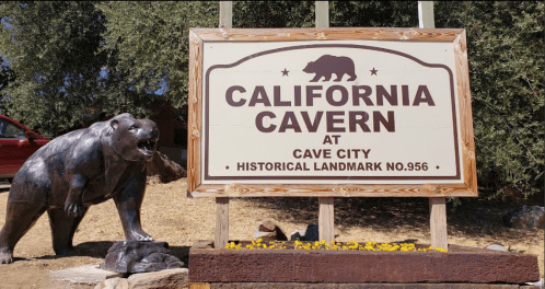 Sign for California Cavern at Cave City, featuring a bear statue and historical landmark designation.