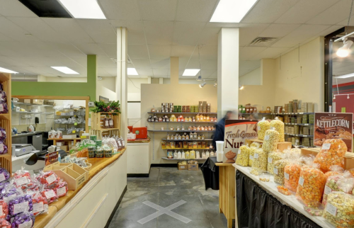 A bright, spacious market with shelves of snacks, nuts, and popcorn, featuring a wooden counter and colorful displays.