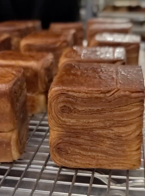 Close-up of neatly stacked, golden-brown laminated dough blocks cooling on a wire rack.