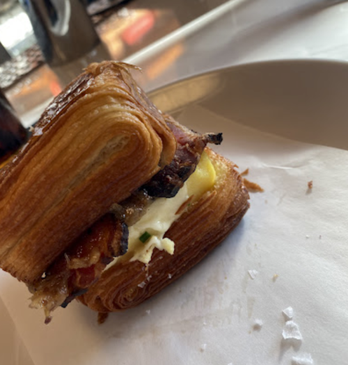 A flaky pastry layered with savory filling, resting on a white paper surface.