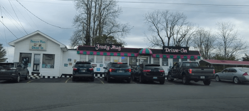 A drive-in restaurant called Frosty Mug, featuring a colorful awning and several parked cars in front.