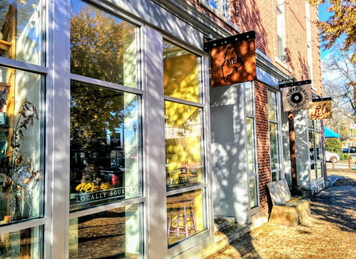 A sunny street view of a storefront with large windows and signs, showcasing a vibrant, inviting atmosphere.