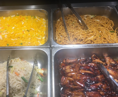 A buffet display with four trays: fried rice, lo mein noodles, stir-fried vegetables, and glazed chicken.