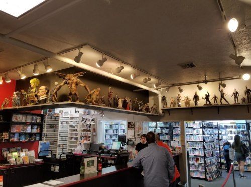 A bookstore interior featuring shelves of action figures and a counter with customers browsing.
