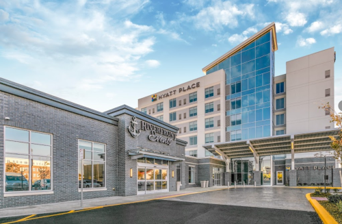 Modern hotel building with a glass facade and entrance, featuring the Hyatt Place sign and a welcoming driveway.