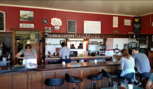 A cozy café interior with a wooden counter, bar stools, and staff preparing drinks in a warm, inviting atmosphere.