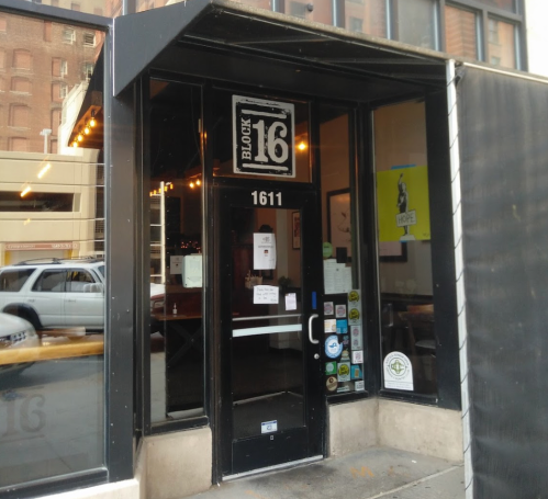 Exterior view of Block 16 restaurant, featuring a black entrance with large windows and a street view.