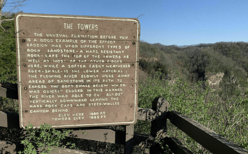 Sign describing "The Towers," a geological formation showcasing erosion effects on sandstone and rock layers.