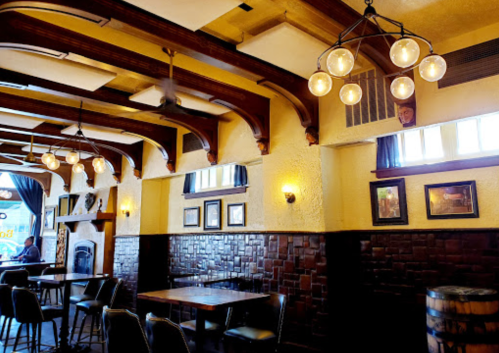Cozy restaurant interior with wooden beams, warm lighting, and tables set against a textured wall.