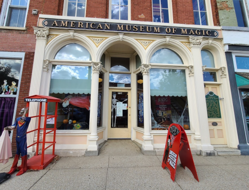 Front view of the American Museum of Magic, featuring a red telephone booth and a sign on the sidewalk.