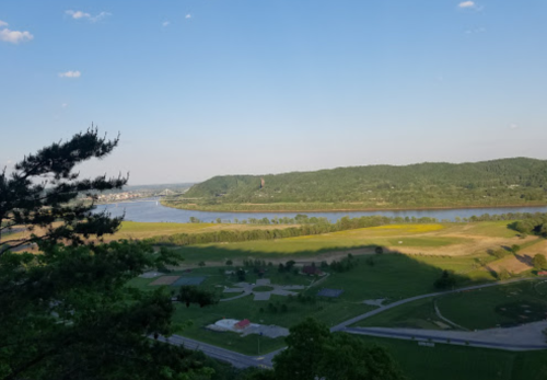 A scenic view of a river winding through green hills and fields under a clear blue sky.