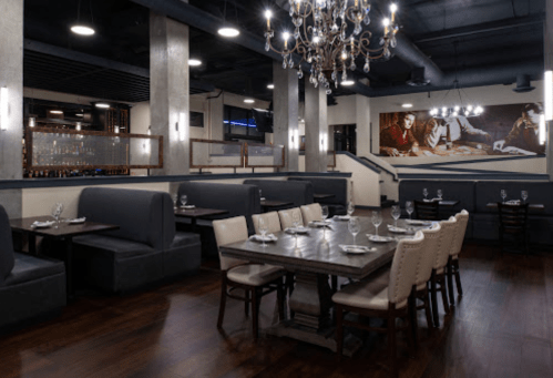 Elegant restaurant interior featuring dark wood floors, plush seating, and a chandelier, with a mural on the wall.
