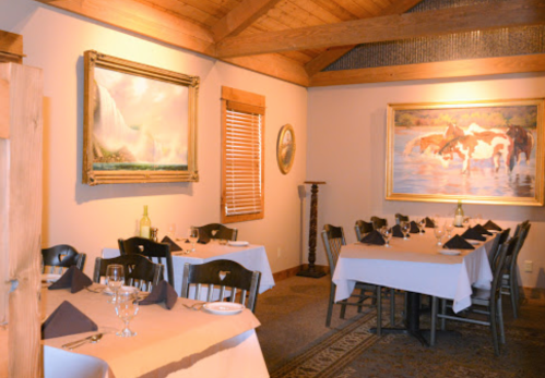 Cozy restaurant interior with wooden beams, tables set for dining, and artwork on the walls.