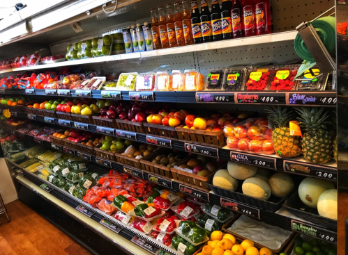 A colorful display of fresh fruits and vegetables in a grocery store, including apples, oranges, and pineapples.