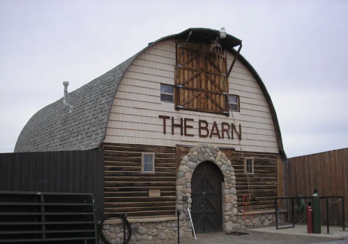 A rustic barn with a stone archway and wooden siding, featuring the words "THE BARN" prominently displayed.