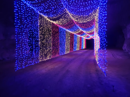 A colorful tunnel illuminated with vibrant blue, purple, and yellow lights, creating a festive atmosphere.