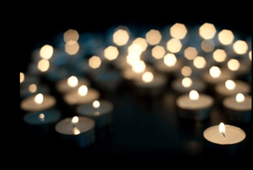 A soft-focus image of numerous lit tealight candles, creating a warm and serene atmosphere.