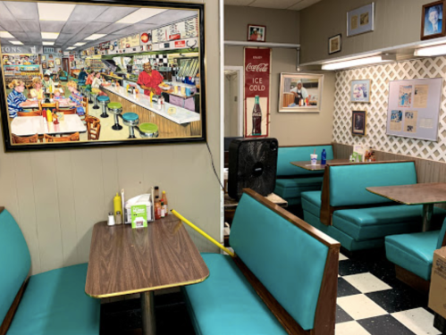 A cozy diner interior featuring teal booths, a vintage painting, and a nostalgic atmosphere.