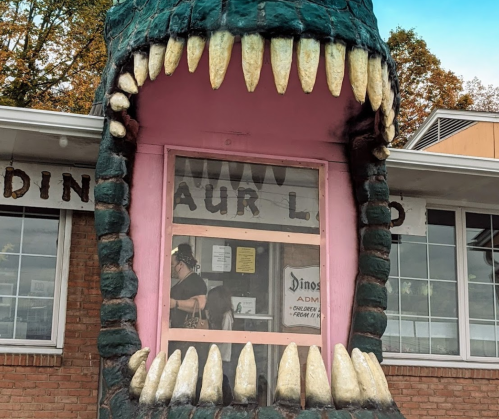 A dinosaur-themed entrance with a large, open mouth and sharp teeth, leading to a ticket window.