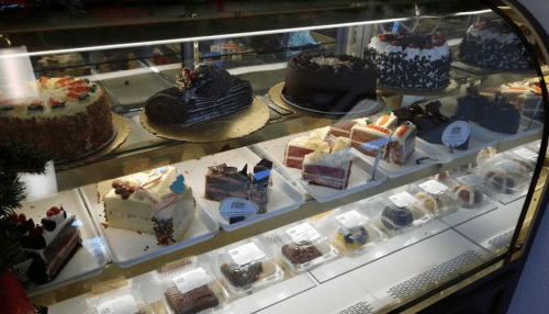 A display case filled with various cakes and pastries, including layered cakes and chocolate desserts.